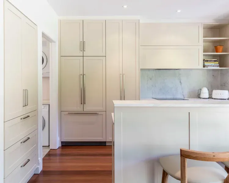Bright modern kitchen with white cabinets, marble backsplash, and warm wood flooring