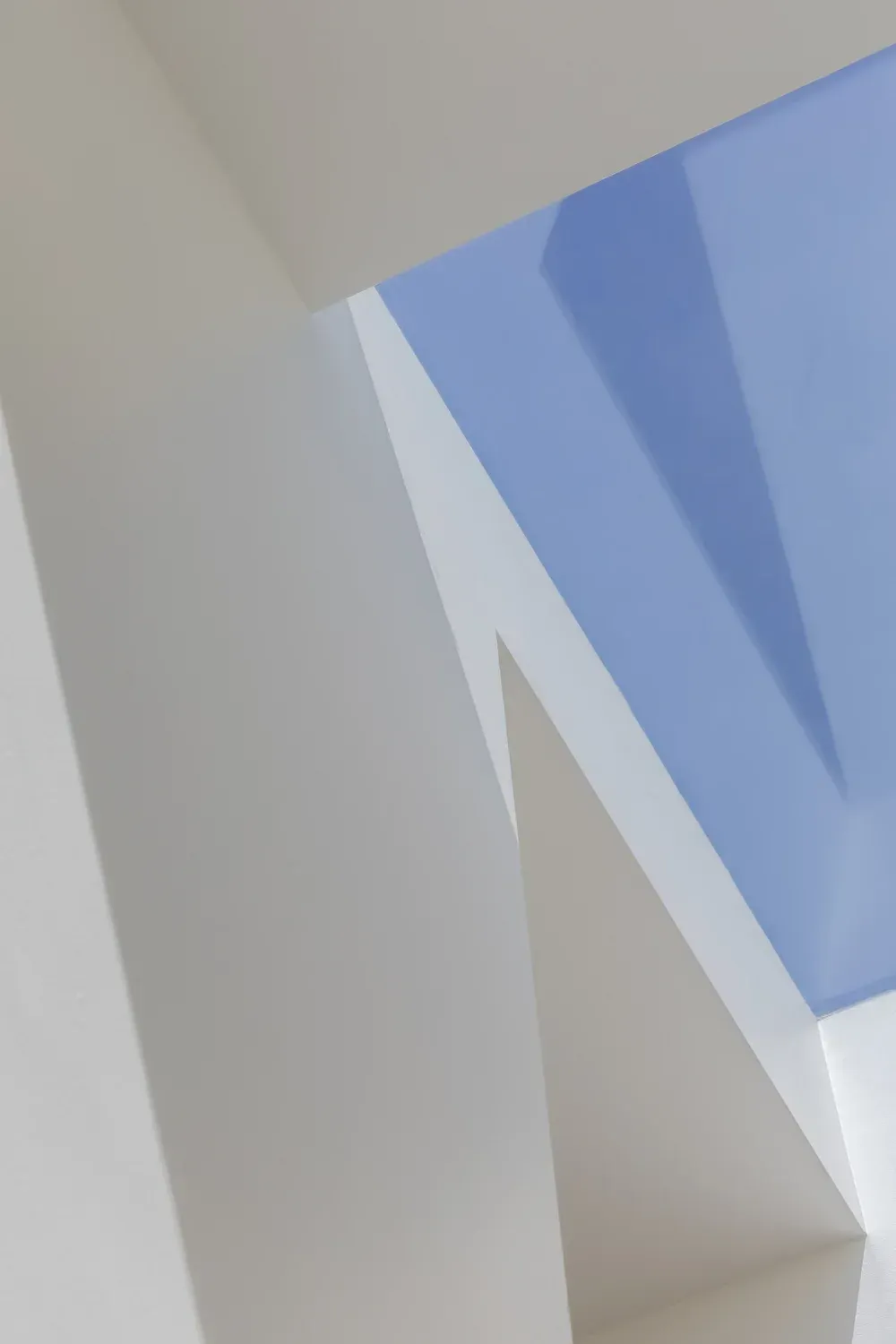 White angular building surfaces against a clear blue sky, viewed from below.