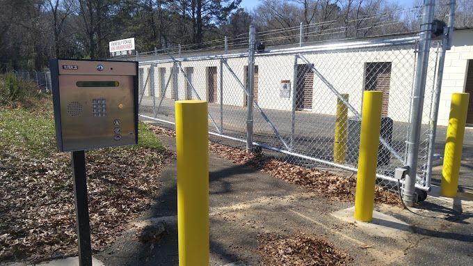 A wooden fence surrounds a driveway with a car parked behind it.