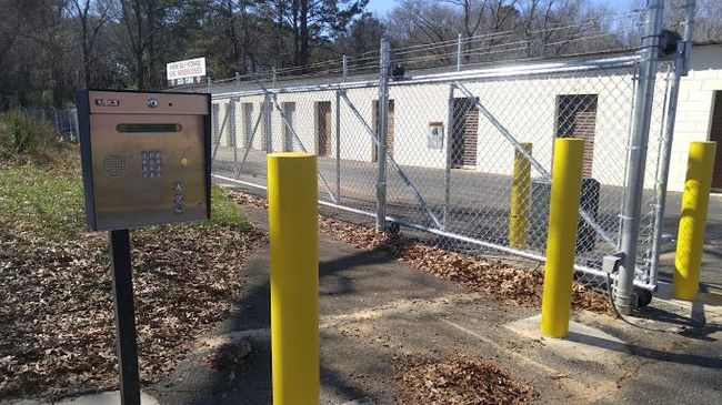 A fence with yellow poles and a mailbox in front of it