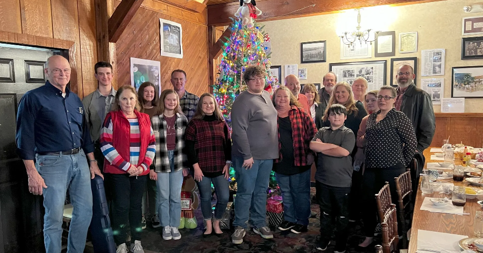 A group of people are posing for a picture in front of a christmas tree.