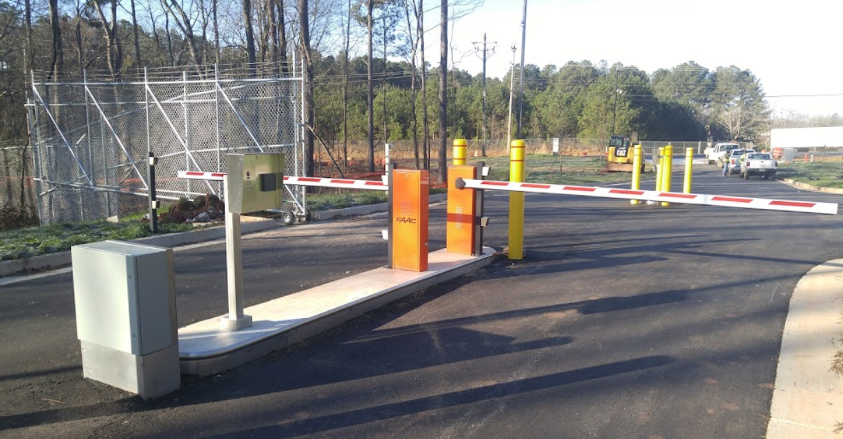 A wooden fence surrounds a driveway with a car parked behind it.