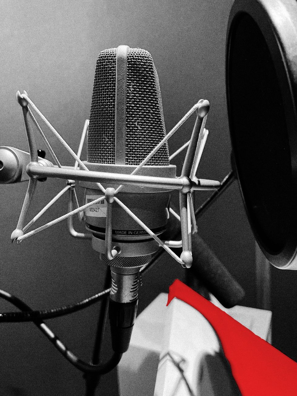 Foto de um microfone em preto e branco com detalhe vermelho