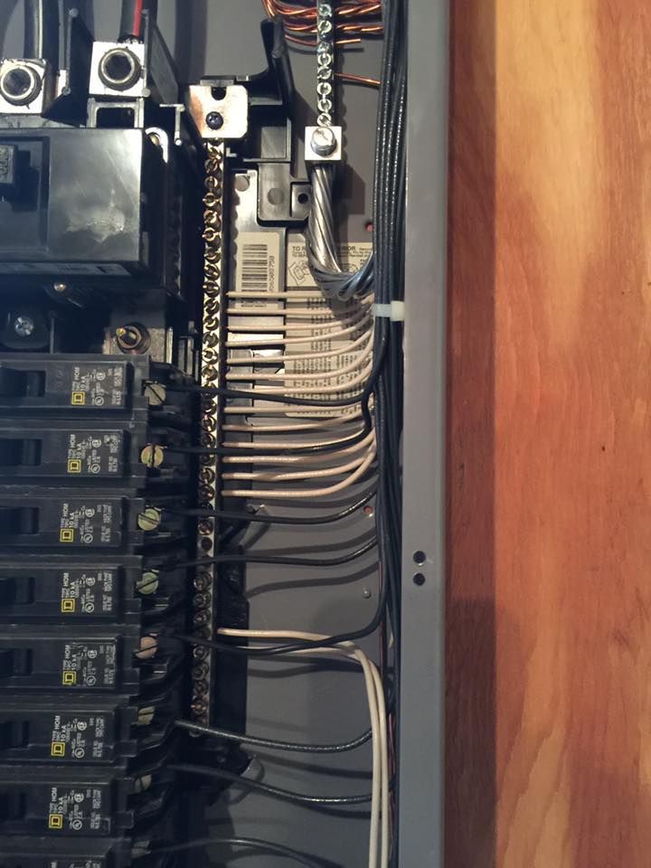 Electrical panel with wires, breakers, and grounding bar.