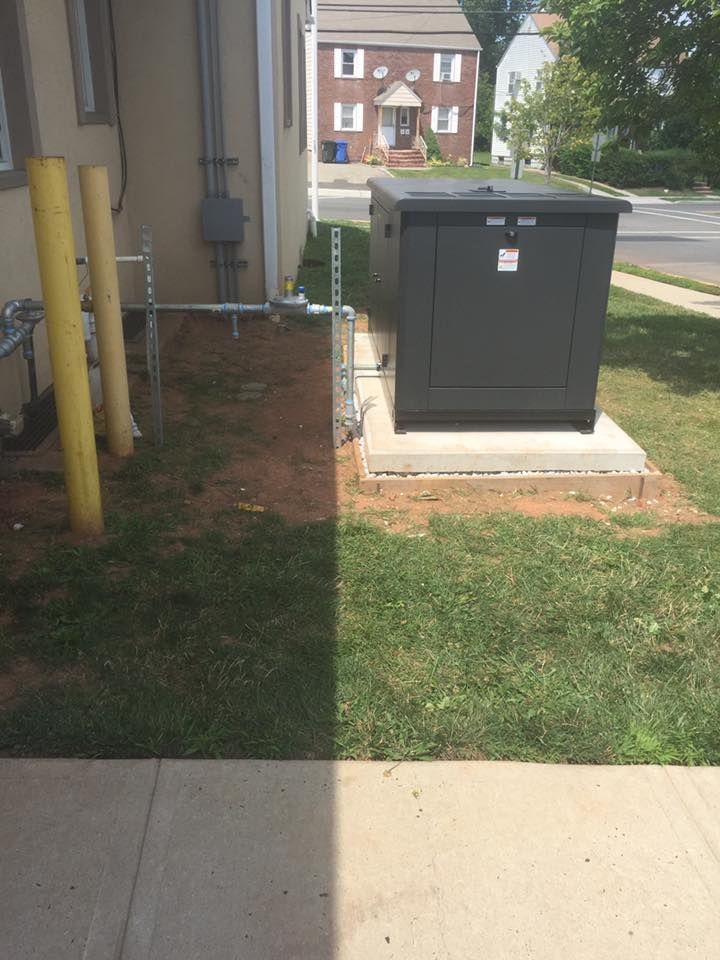 A large gray electrical box on a concrete pad next to a building with yellow bollards.