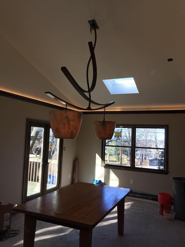 Dining room with wooden table, modern chandelier, window, and door.