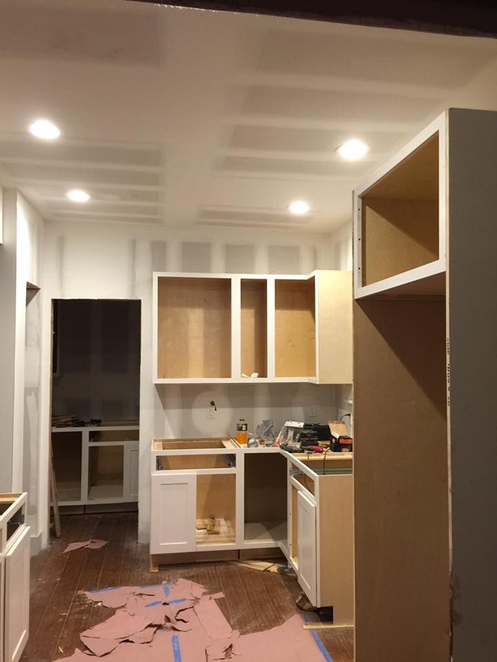 Kitchen renovation in progress: cabinets, unfinished walls, drywall, and exposed wood.