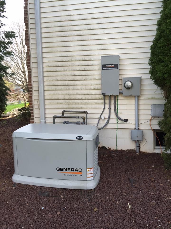 A Generac generator installed outside a house with electrical components on the siding.