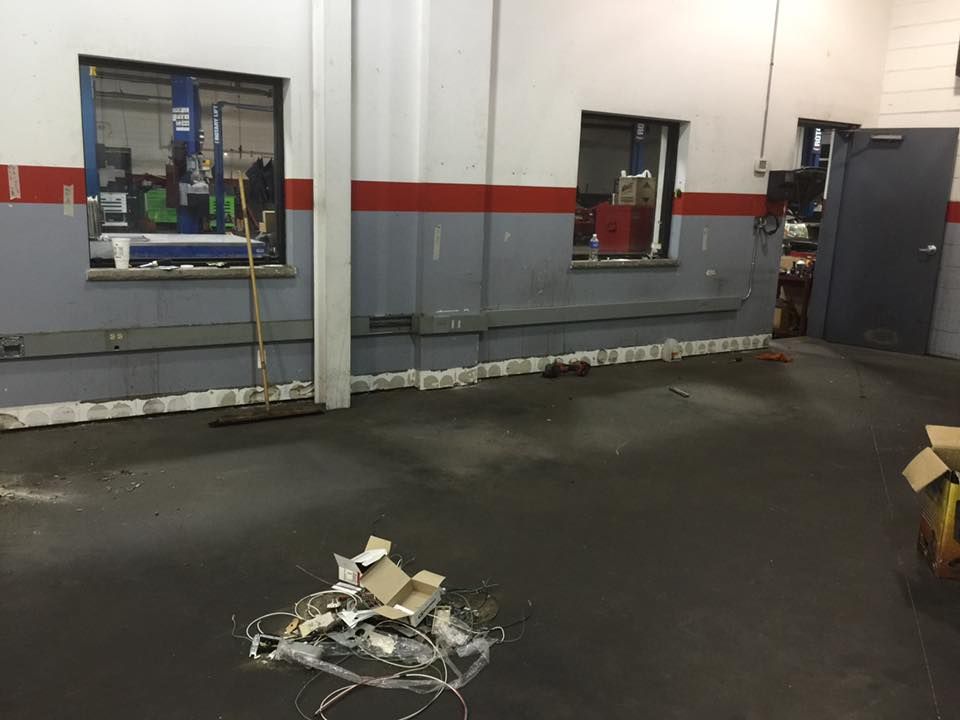 An interior shot of a garage. A pile of debris on the floor, two windows, a door.