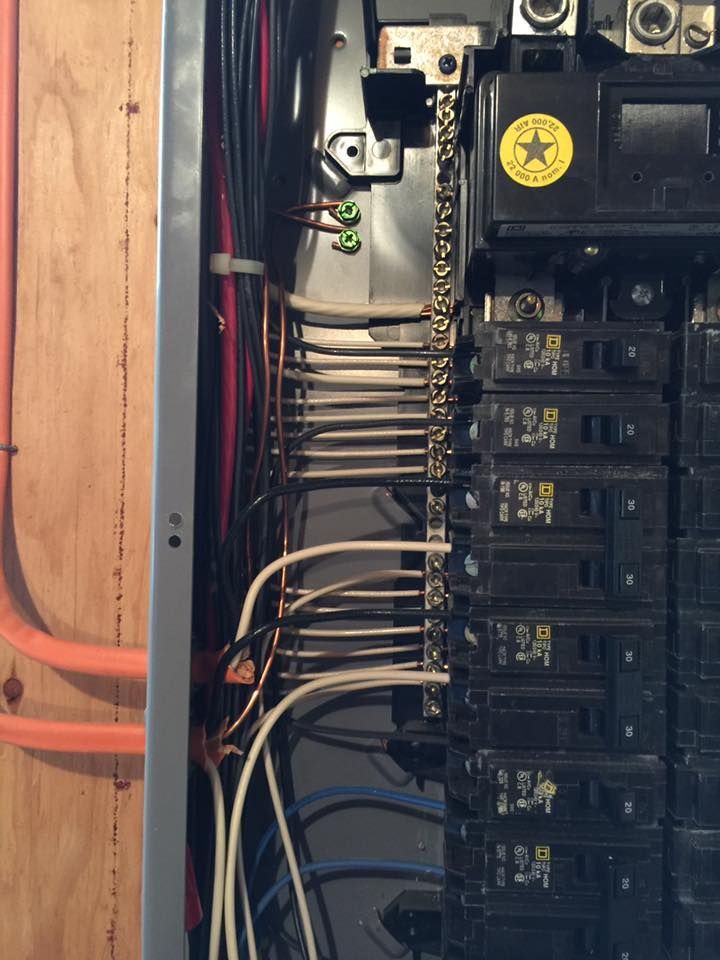 Electrical panel with wires, breakers, and a ground bar.
