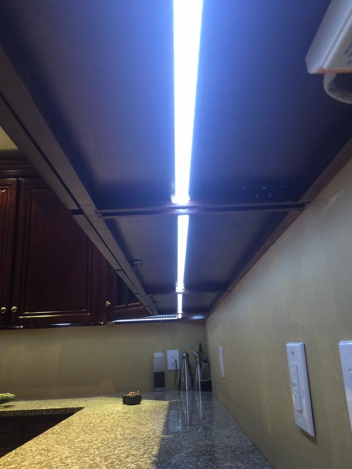 Bright overhead lights illuminate a kitchen countertop. Brown cabinets and tan walls.
