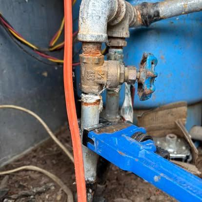 A close up of a water pipe with a wrench attached to it.