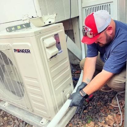 A man is working on a pioneer air conditioner outside of a building.