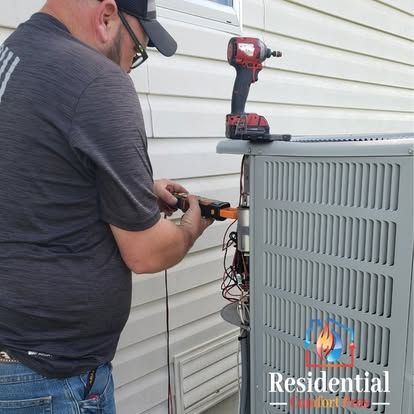 A man is working on an air conditioner outside of a house.