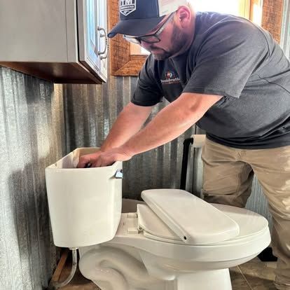 A man is fixing a toilet in a bathroom.