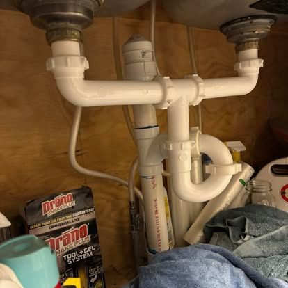 A kitchen sink with a lot of pipes underneath it