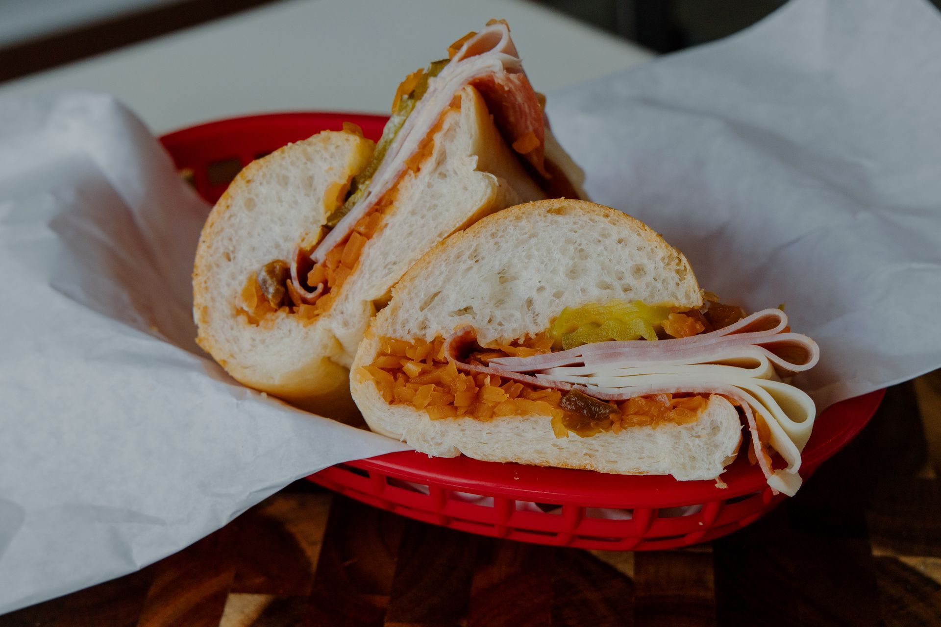 Sliced sandwich in a red basket lined with white paper.