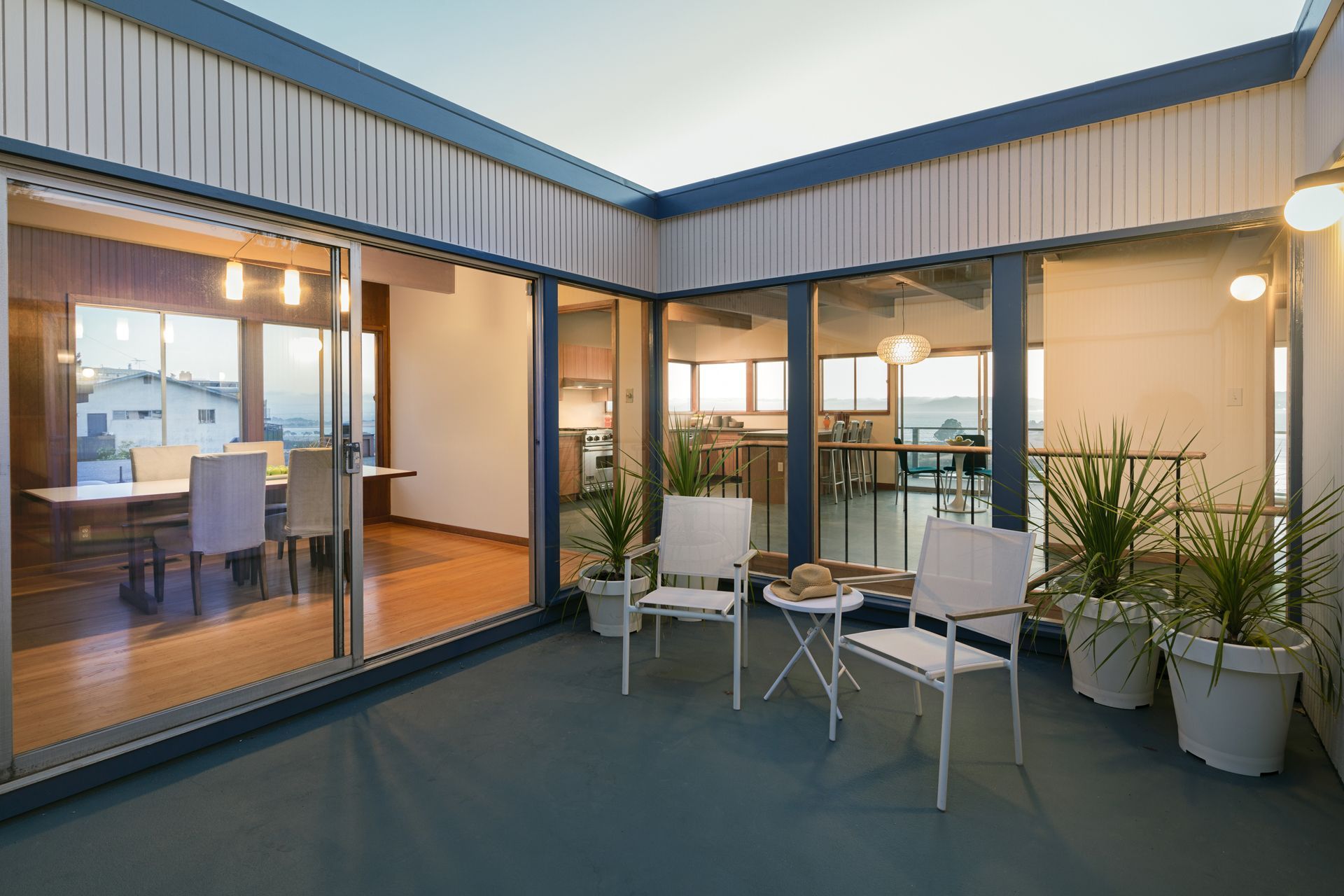 A Balcony With Chairs and a Table in a House With a Lot of Windows