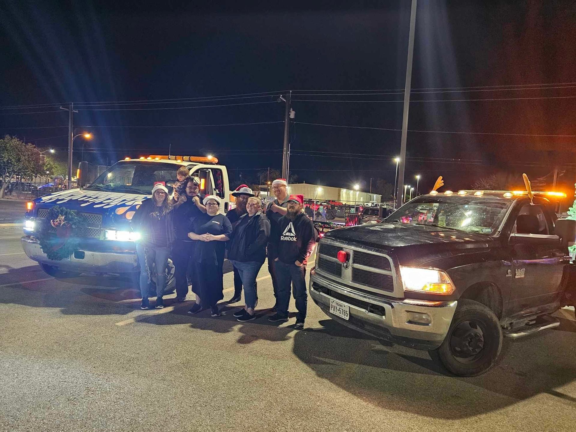 Group of people standing with decorated trucks at night.