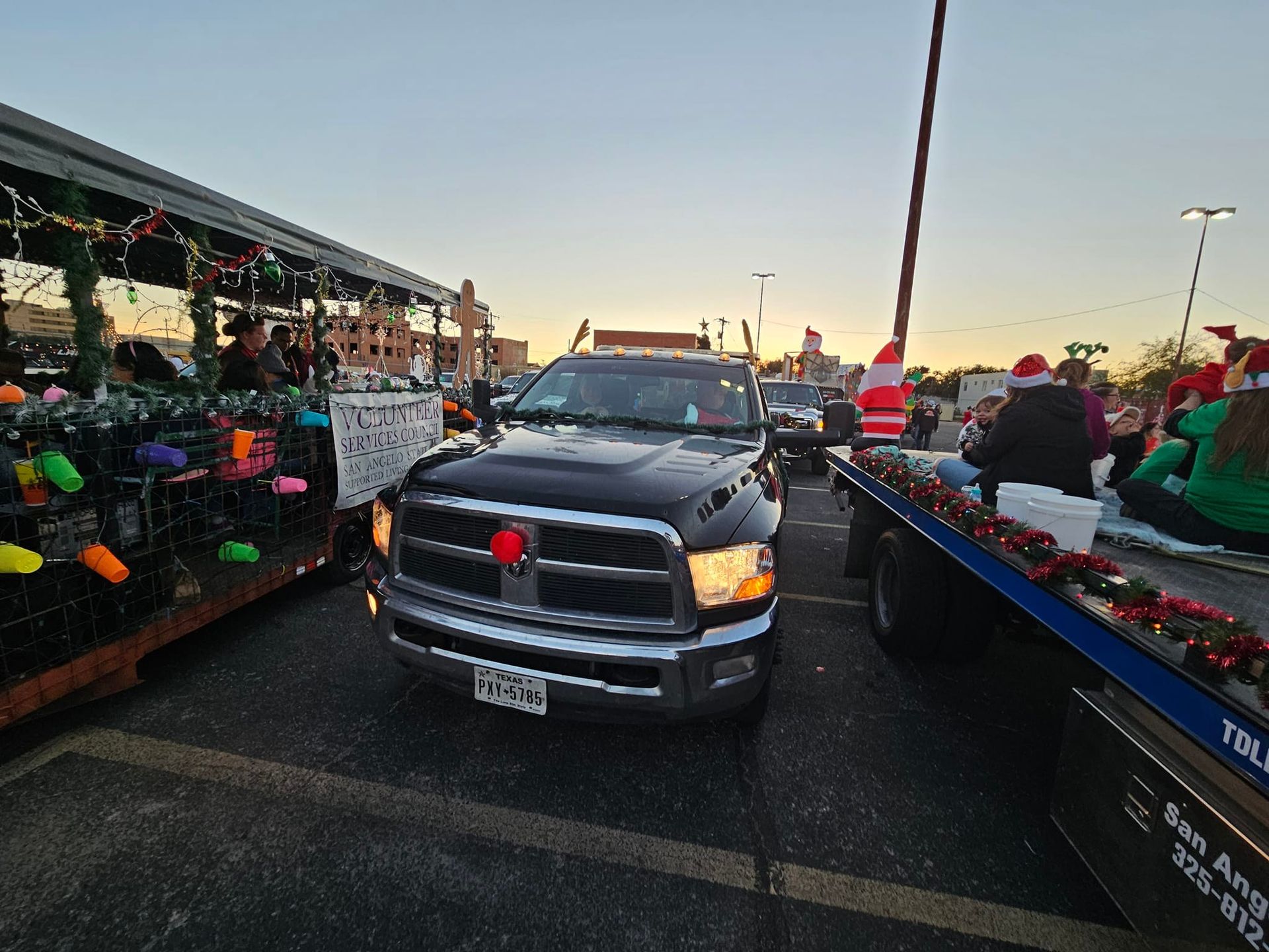 Black truck with a red nose leading a Christmas parade.