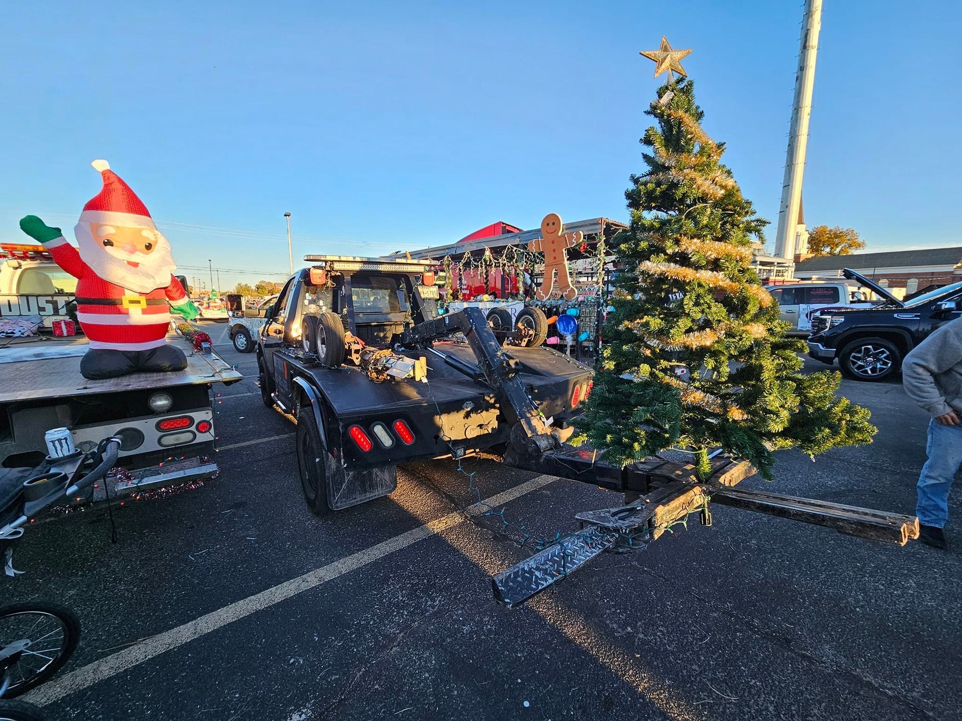 A tow truck decorated with a Christmas tree and inflatable Santa.