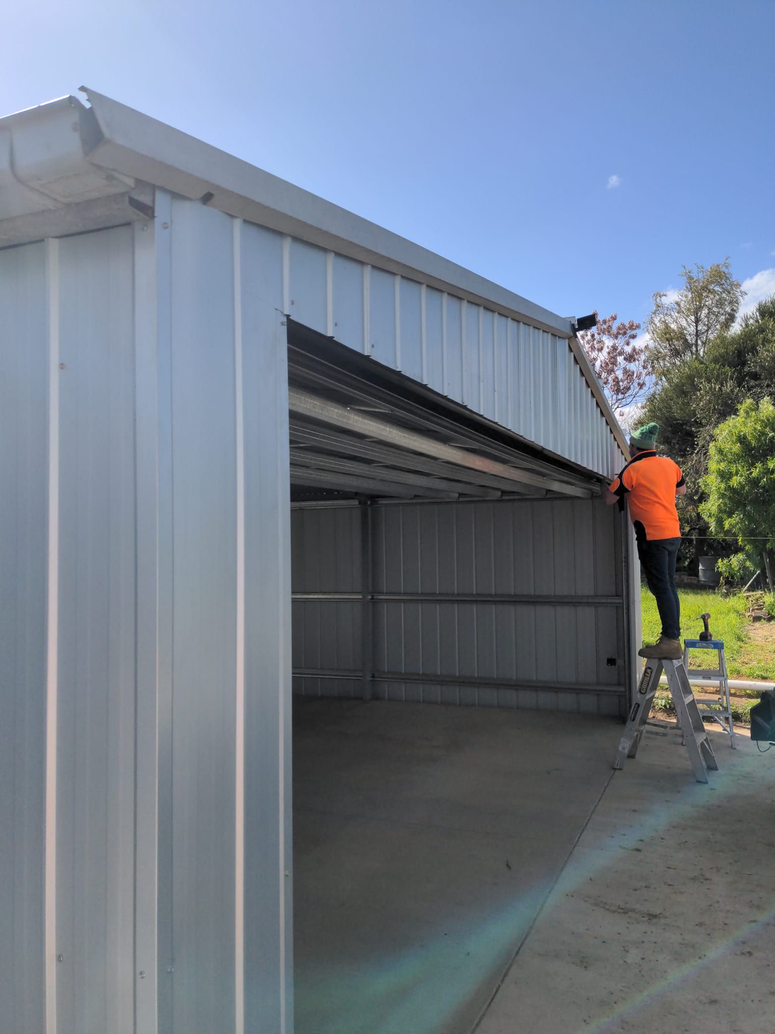 A Man is Fixing a Garage Door Spring With a Wrench — Goldfields Garage Doors & Gates in Wendouree, VIC