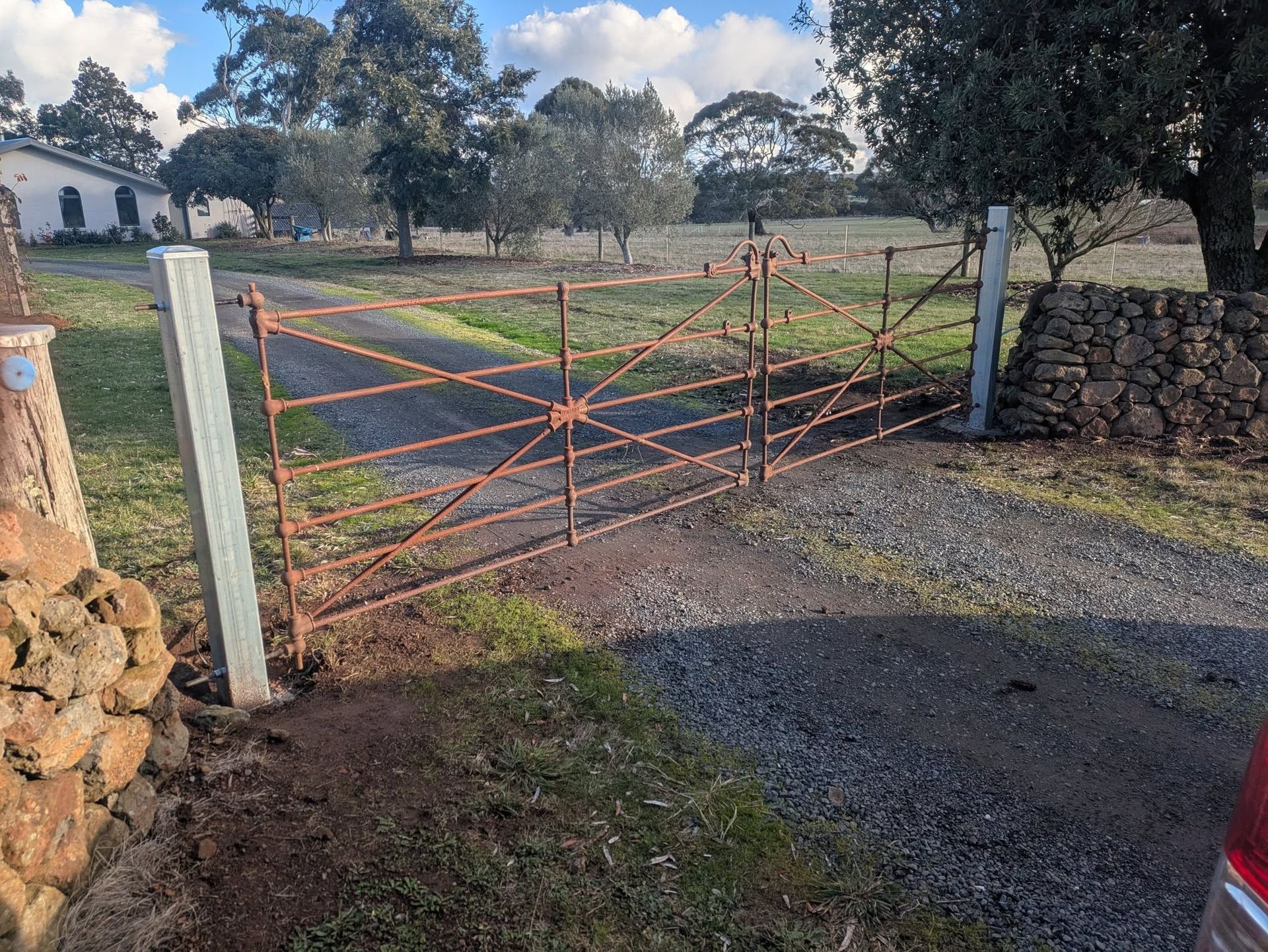 Rusty Metal Gate Open on a Gravel Driveway — Goldfields Garage Doors & Gates in Wendouree, VIC