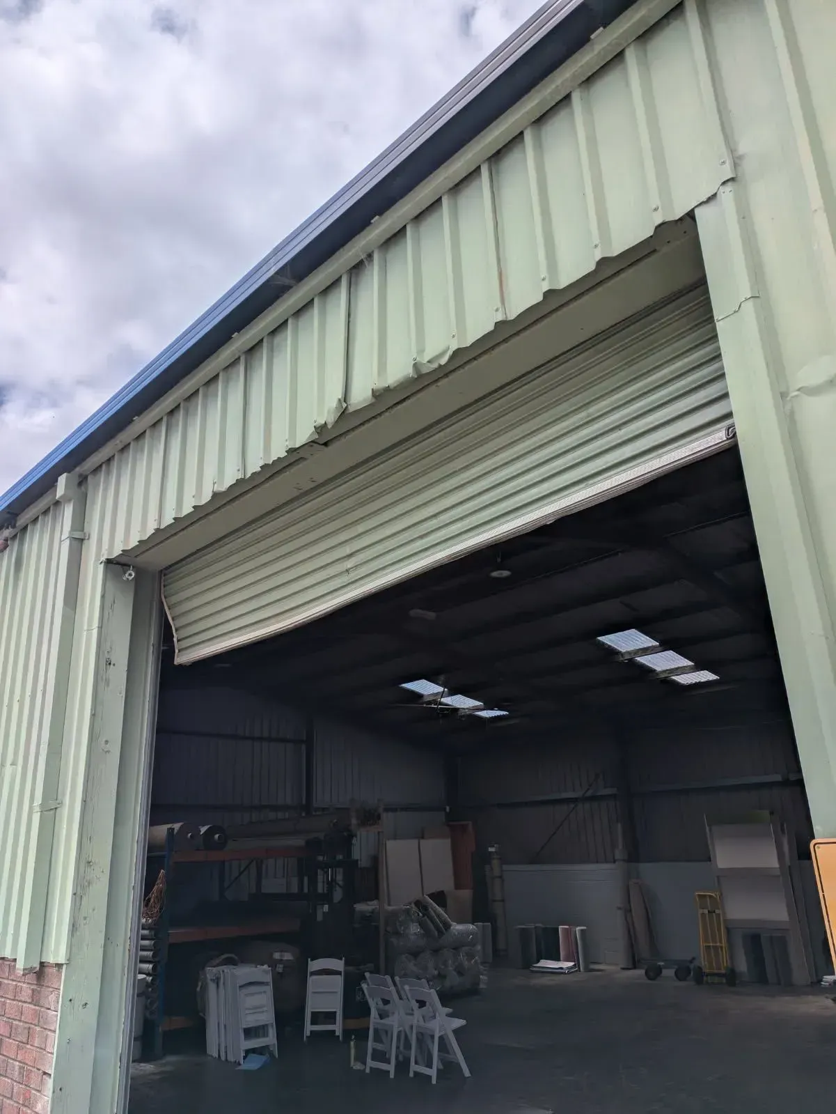 Gray Automatic Driveway Gate Between a White Building and a Brick Wall — Goldfields Garage Doors & Gates in Wendouree, VIC