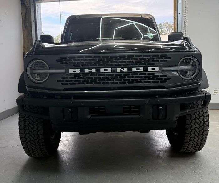 A front-facing view of a black Ford Bronco parked inside a garage.