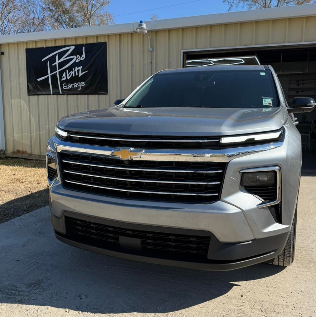 A silver Chevrolet Tahoe parked in front of a building with a 