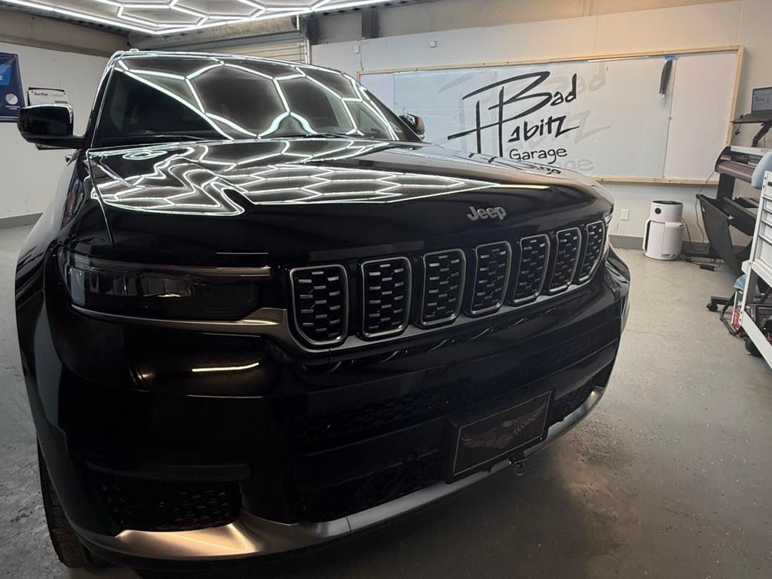 A polished black Jeep SUV parked in a garage with a signed whiteboard in the background.