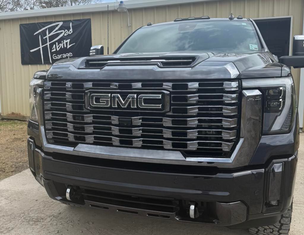 A dark gray GMC pickup truck parked in front of a metal building with a 