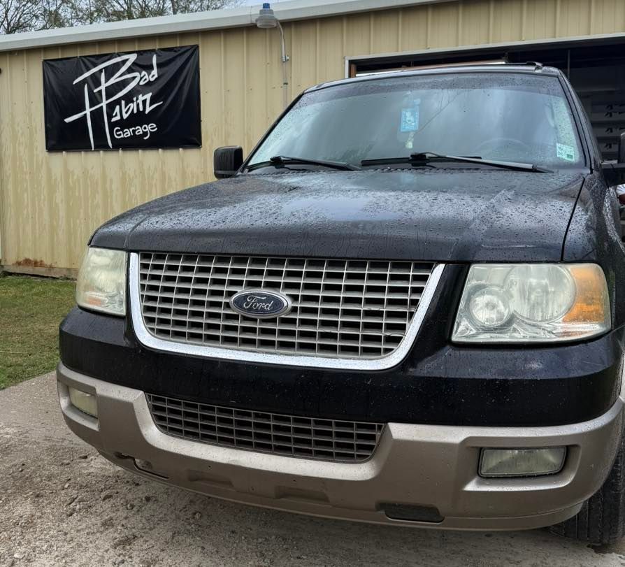 A black Ford Expedition with a tan bumper parked in front of a building with a 