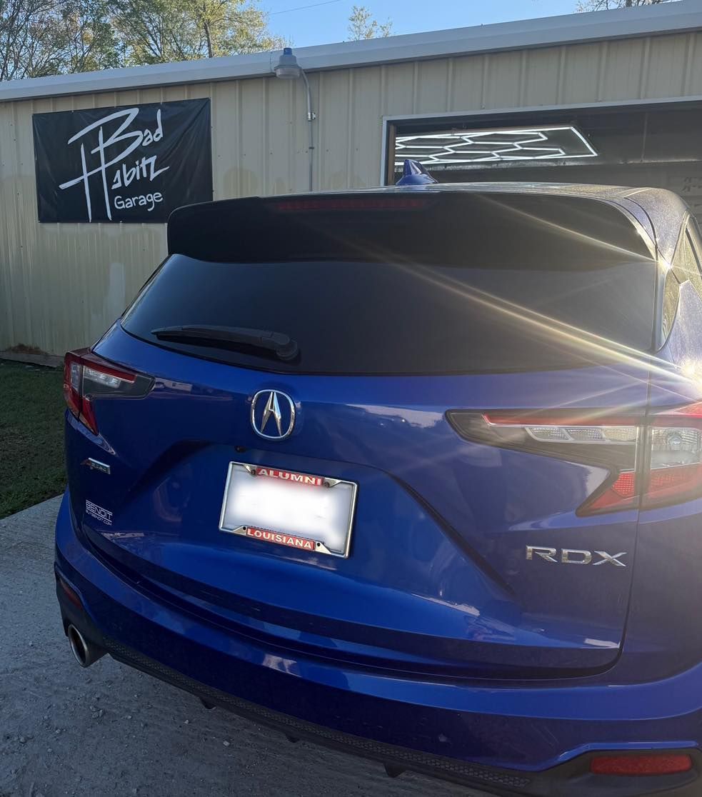 A blue Acura RDX SUV parked in front of a building with a 