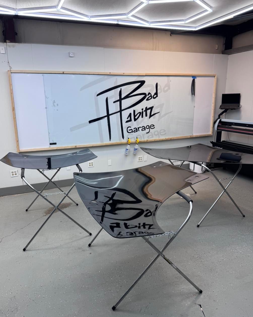 Three car bumpers on metal stands in a garage with 