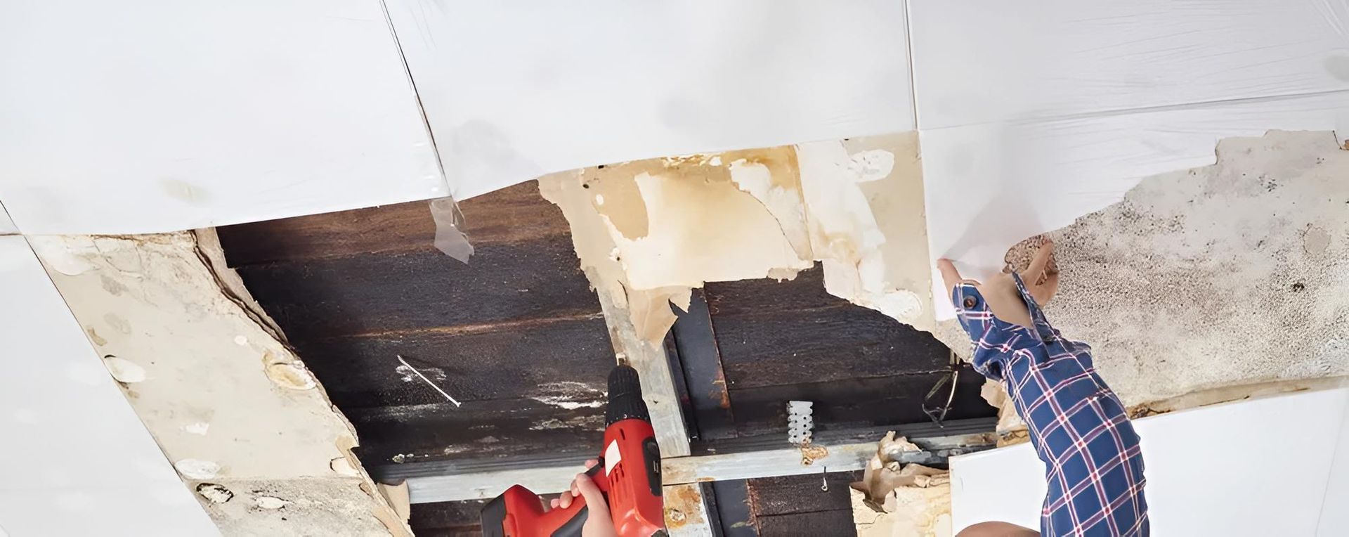 A Person Repairs a Damaged Ceiling, Exposing Wooden Beams — Darwin Plumbing Maintenance in Knuckey Lagoon, NT