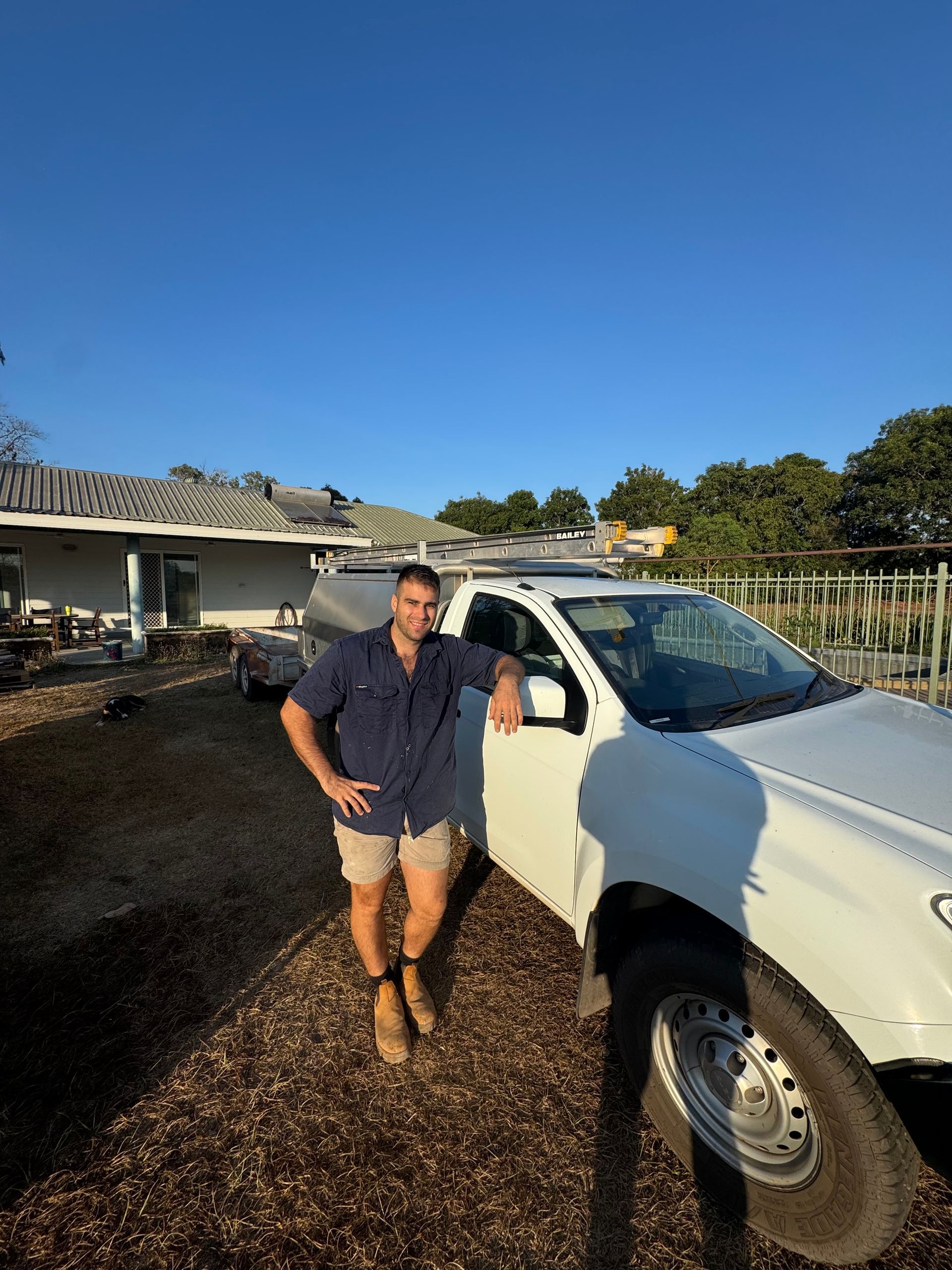 Man leans on white pickup truck, wearing shorts and blue shirt outdoors. — Darwin Plumbing Maintenance in Knuckey Lagoon, NT