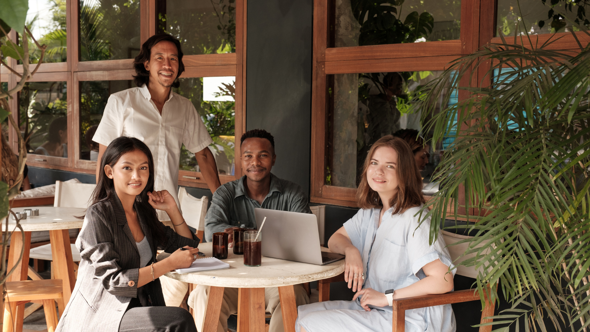 A group of people are sitting around a table with laptop 