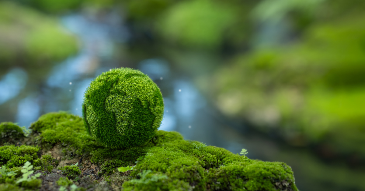 Earth made out of green grass and moss, sitting on a mossy ledge.