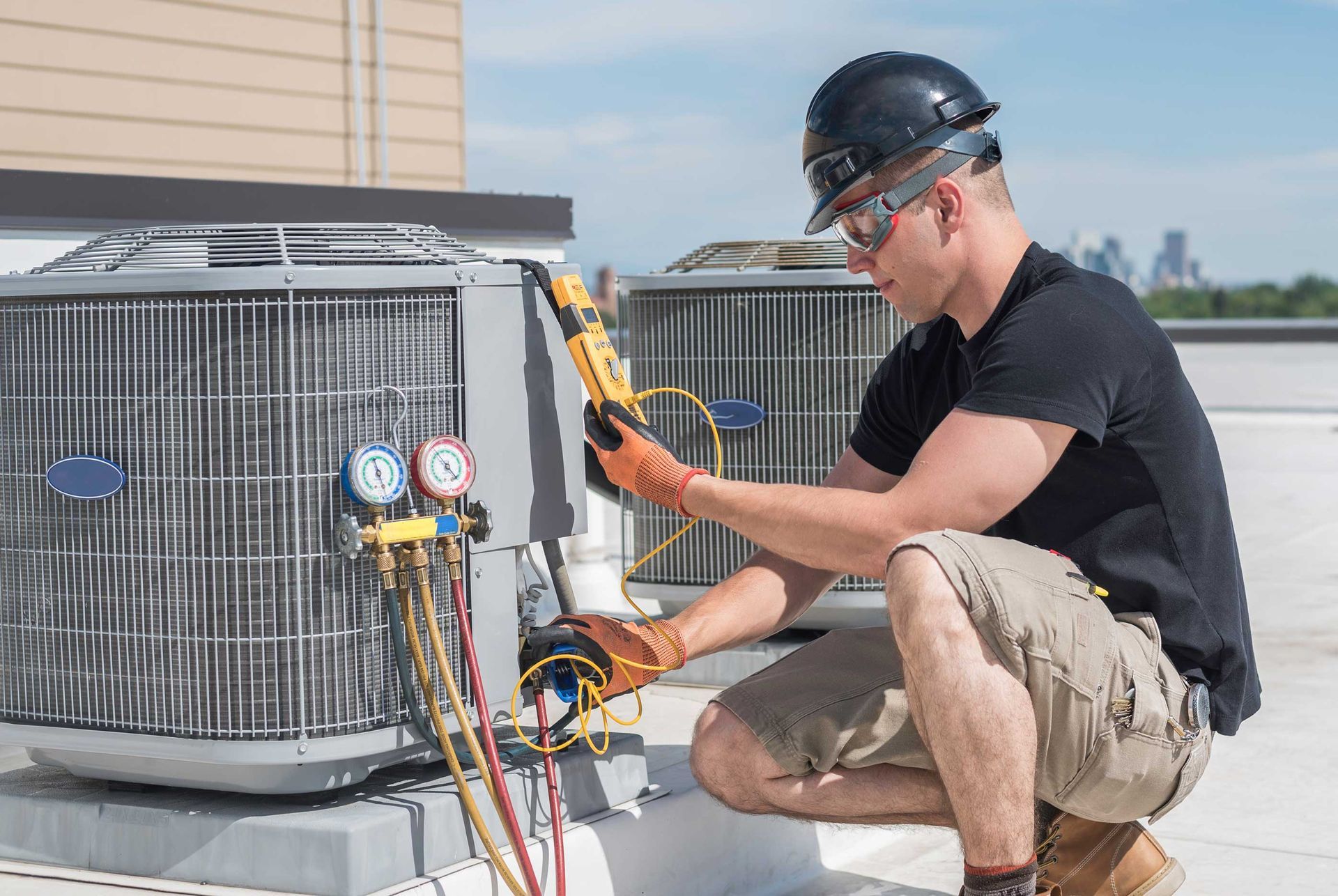 HVAC technician inspects rooftop air conditioning unit, using a meter and gauges.