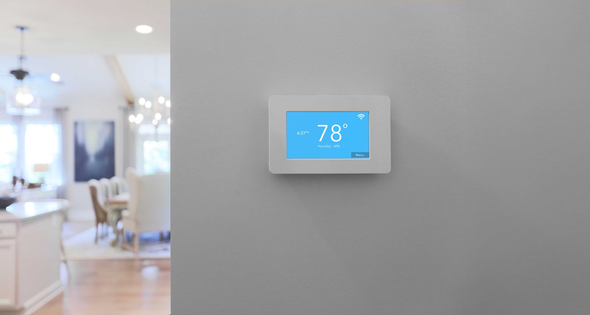 White thermostat displaying 78 degrees mounted on a gray wall in a home.