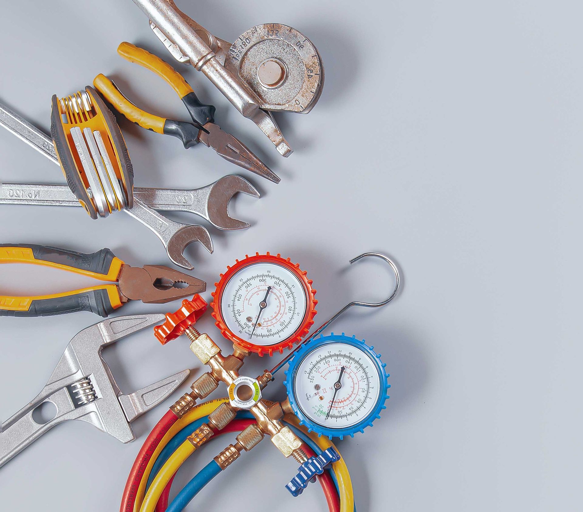 Tools for HVAC repair, including gauges, wrenches, and pliers, against a gray background.