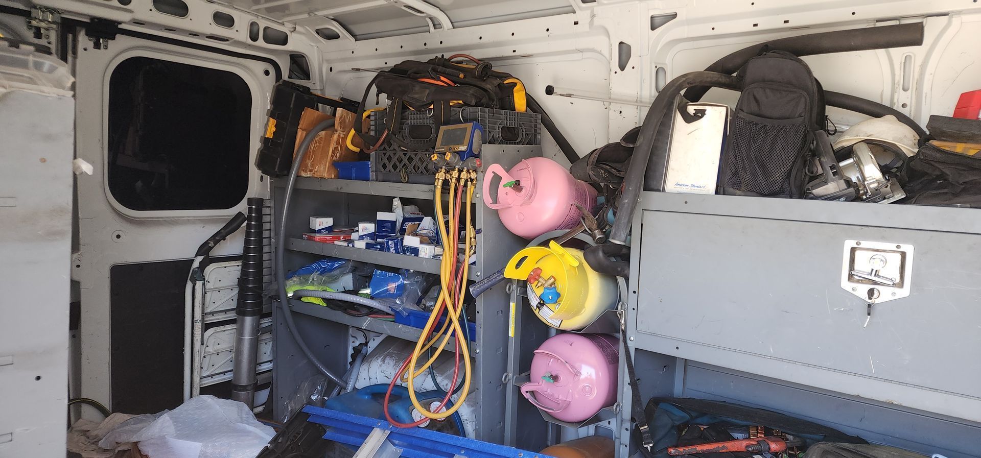Inside of a cargo van, with shelves containing tools, cords, and pink and yellow decorative items.