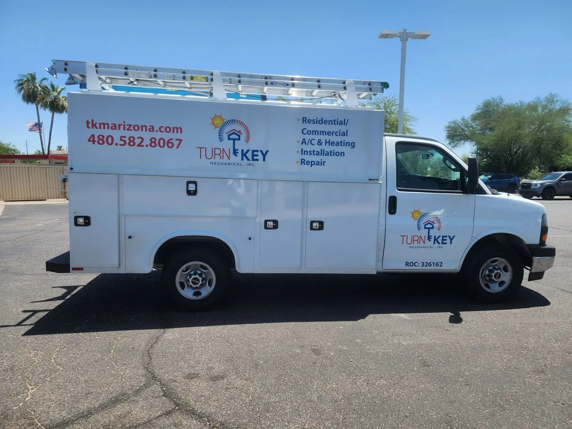 White service truck with ladder on top, labeled Turn Key with contact info, parked outdoors.