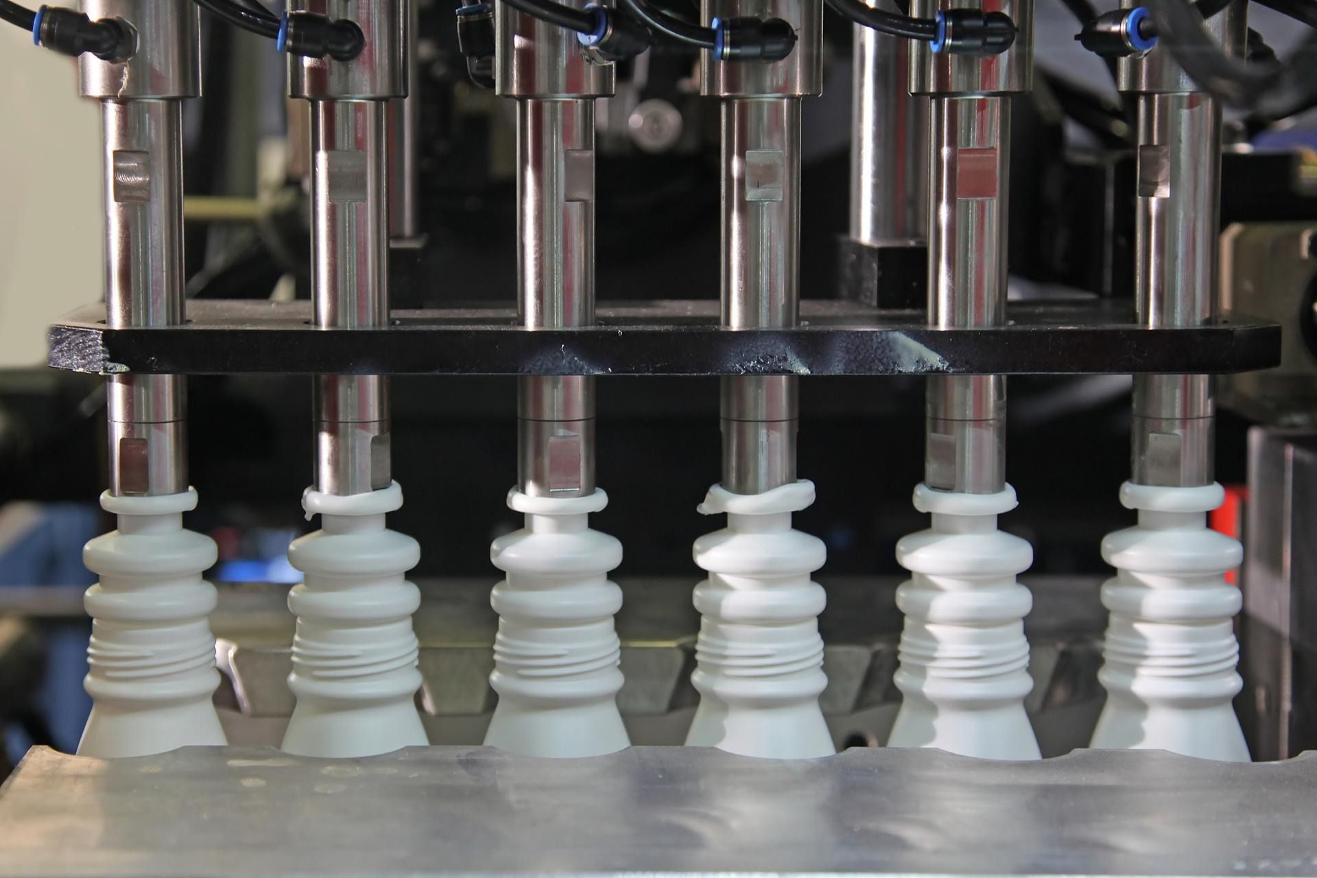 Una fila di bottiglie di plastica bianca vengono riempite su una linea di produzione automatizzata in fabbrica.