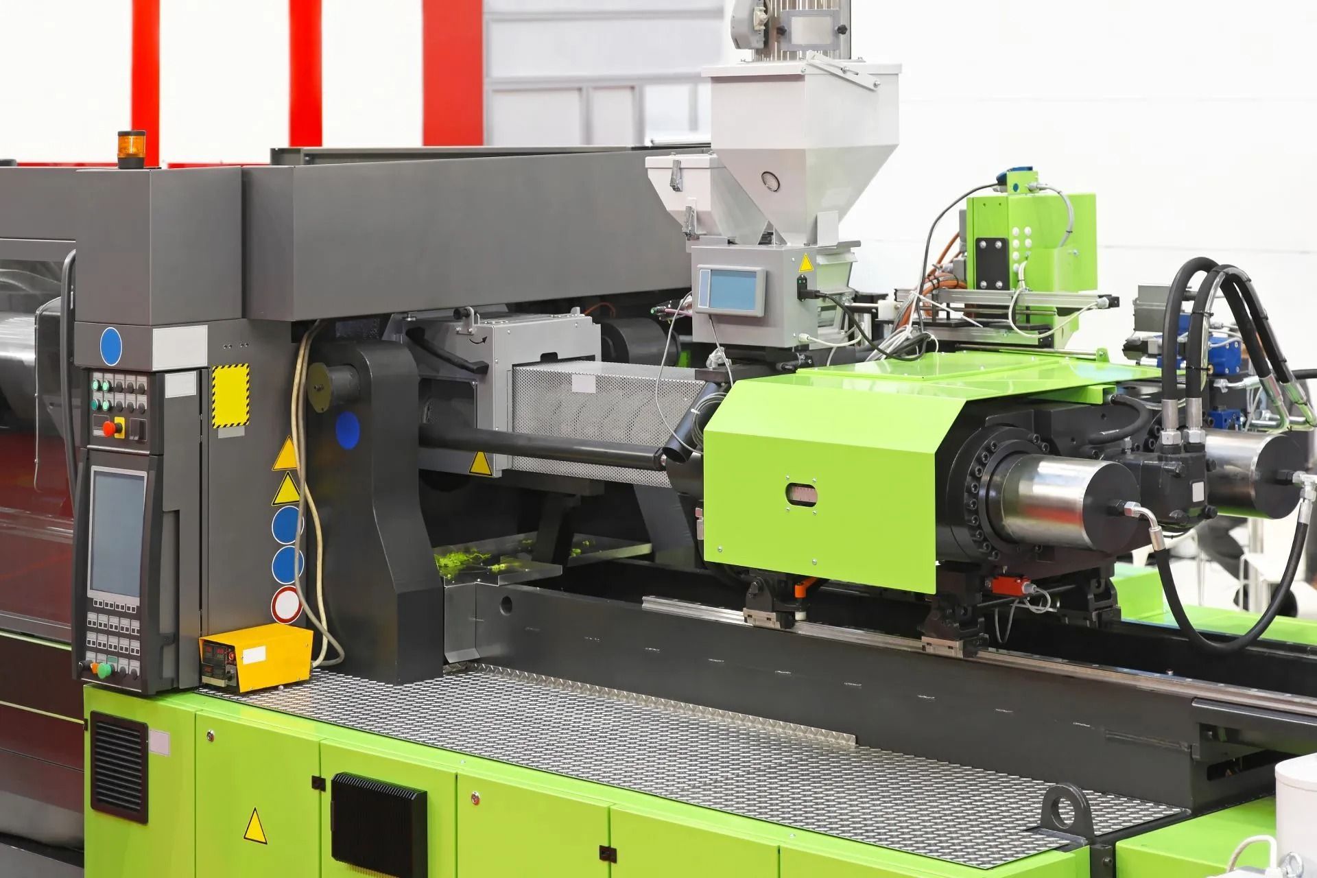 Macchina per stampaggio a iniezione industriale in una fabbrica, con componenti verde brillante e neri e superficie del nastro trasportatore in metallo.