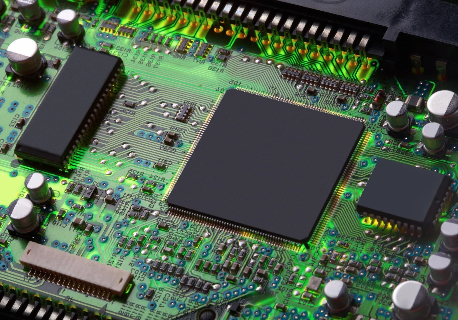 Primo piano di un circuito stampato verde con chip e connettori neri.