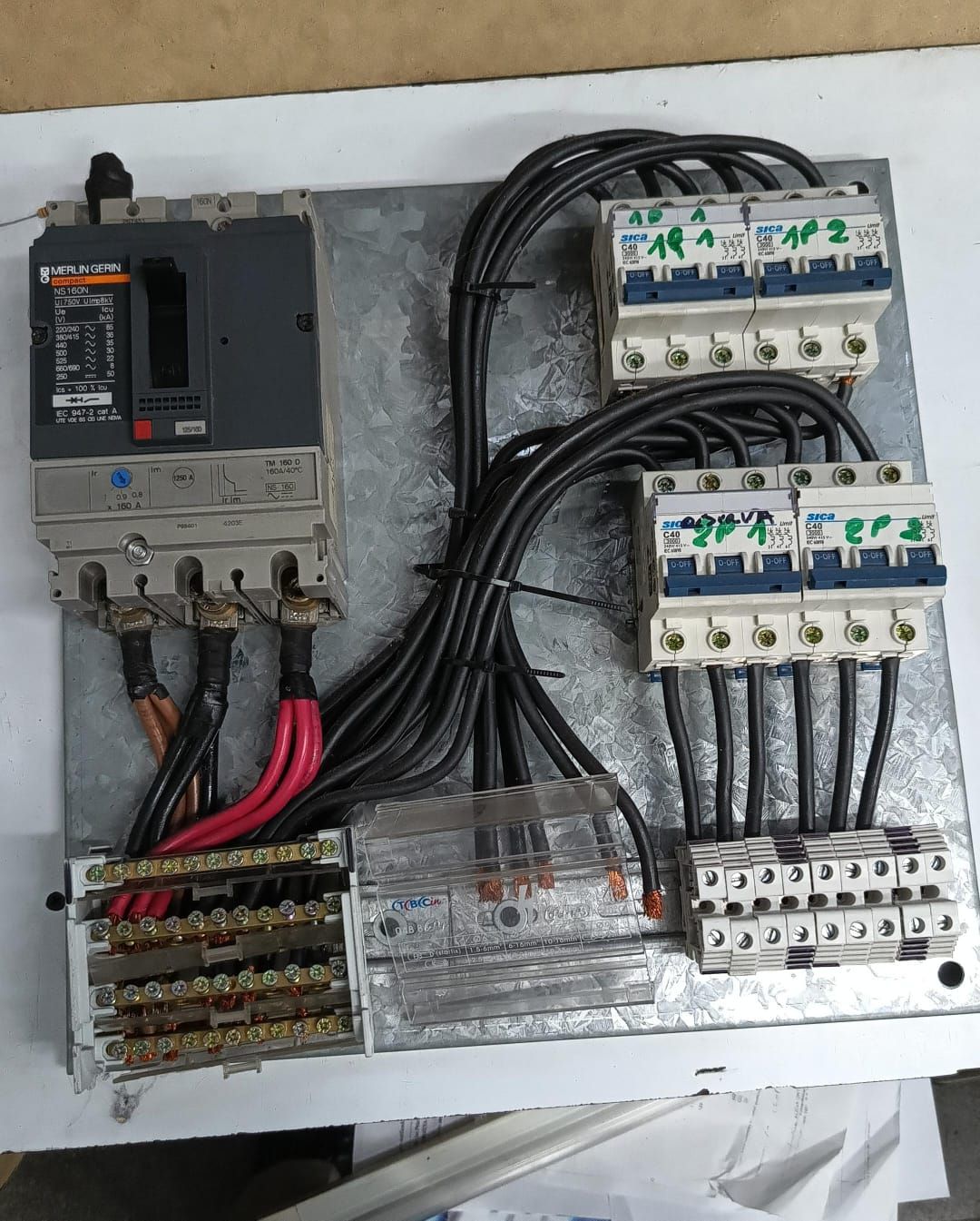 Instalación de fontanería debajo del fregadero con tuberías, botellas de limpieza y un cubo de basura en un área de armarios.