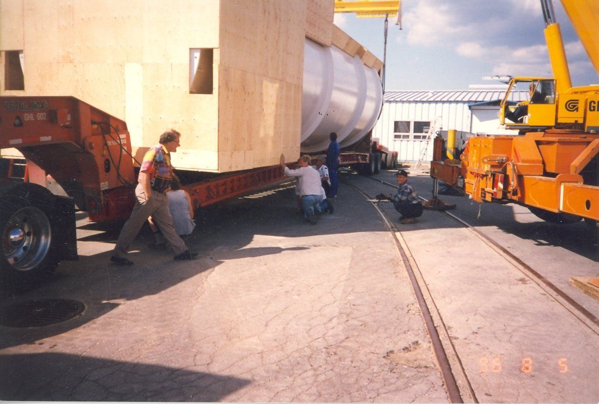 A yellow crane is lifting a large piece of wood