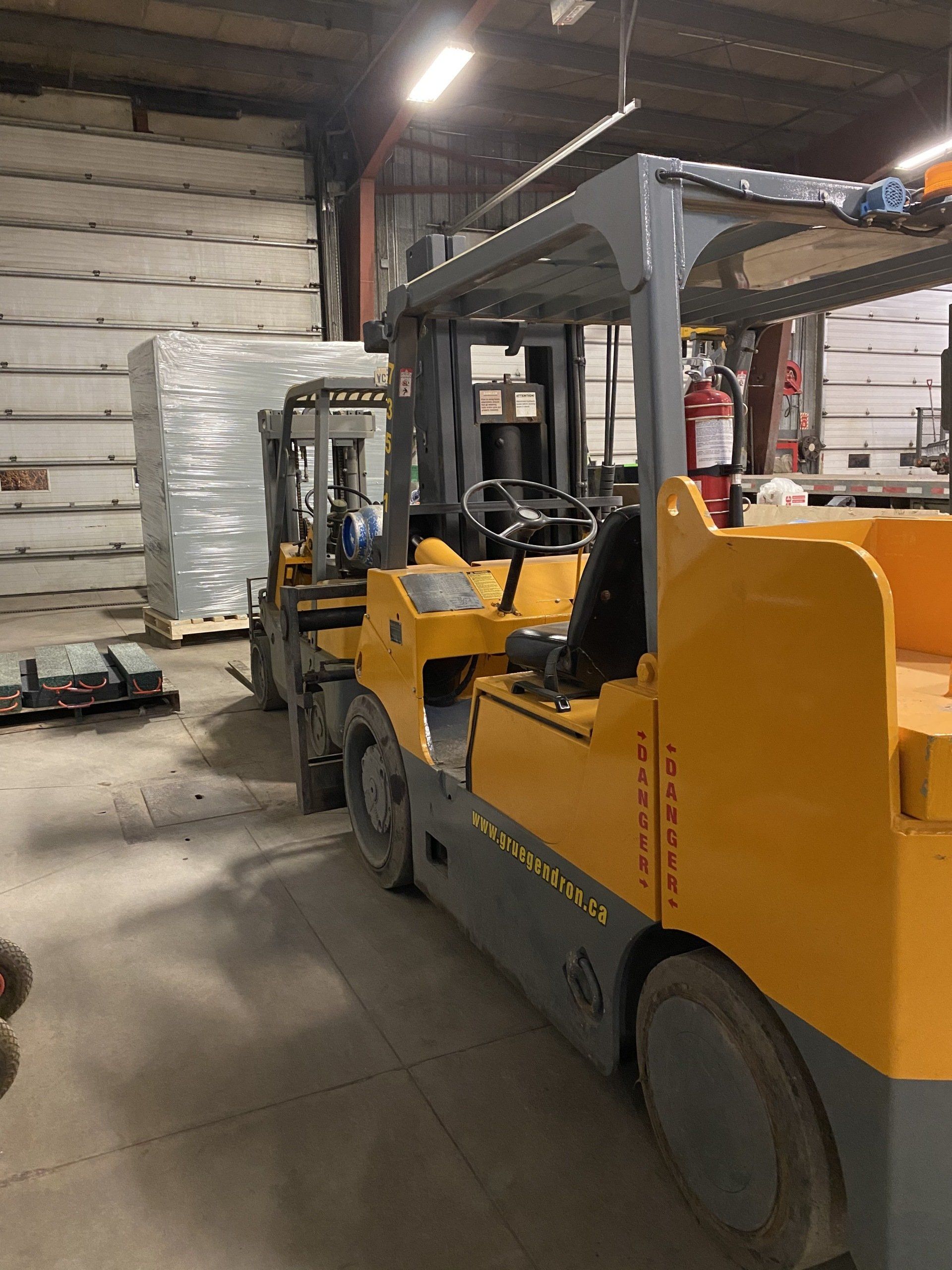 Une rangée de chariots élévateurs est garée dans un entrepôt